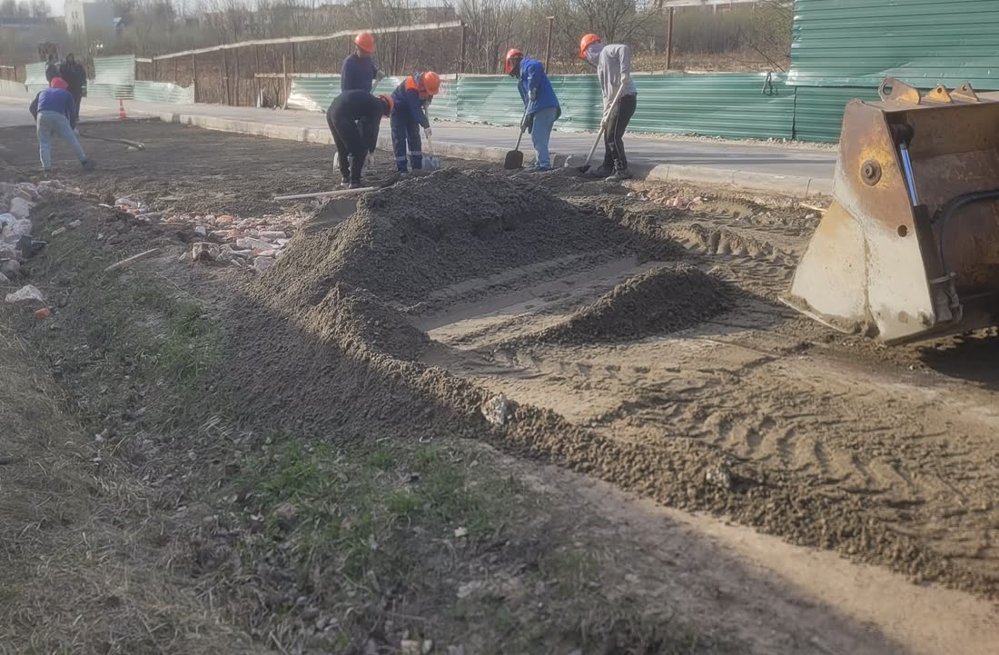 Бригада вручную готовит основание и распределяет материалы перед дорожными работами